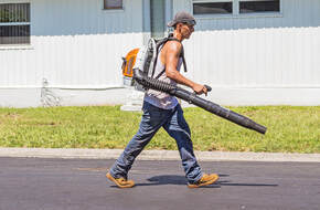 Picture of a man cleaning the yard after lawn mowing